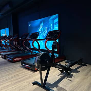 Cardio-Bereich mit Trainingsgeräten vor Bildschirm Cardiogeräte vor Bildschirm
