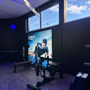 Trainingsplatz mit Motivationsbanner Hantelbank vor Bildschirm