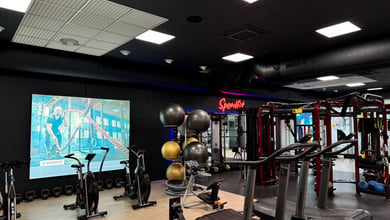 Cardio- und Trainingsgeräte vor großer Projektionsleinwand Geräte vor Projektionswand