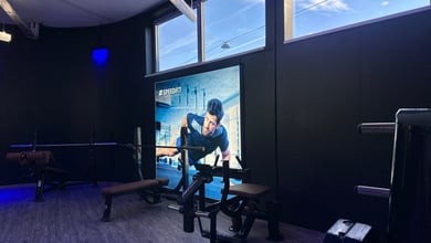 Trainingsplatz mit Motivationsbanner Hantelbank vor Bildschirm